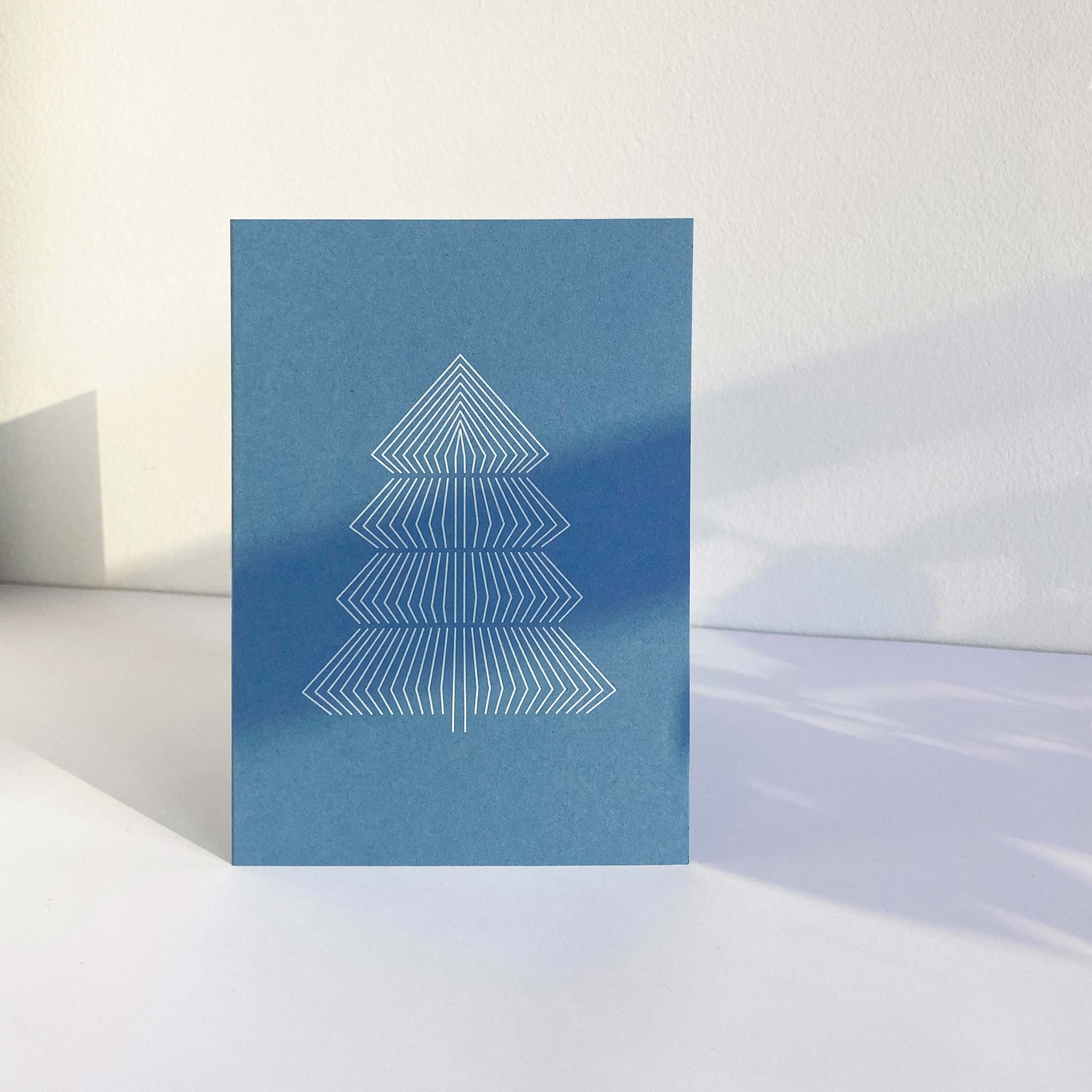 Standing sky blue A6 christmas greeting card with graphic print of fir tree