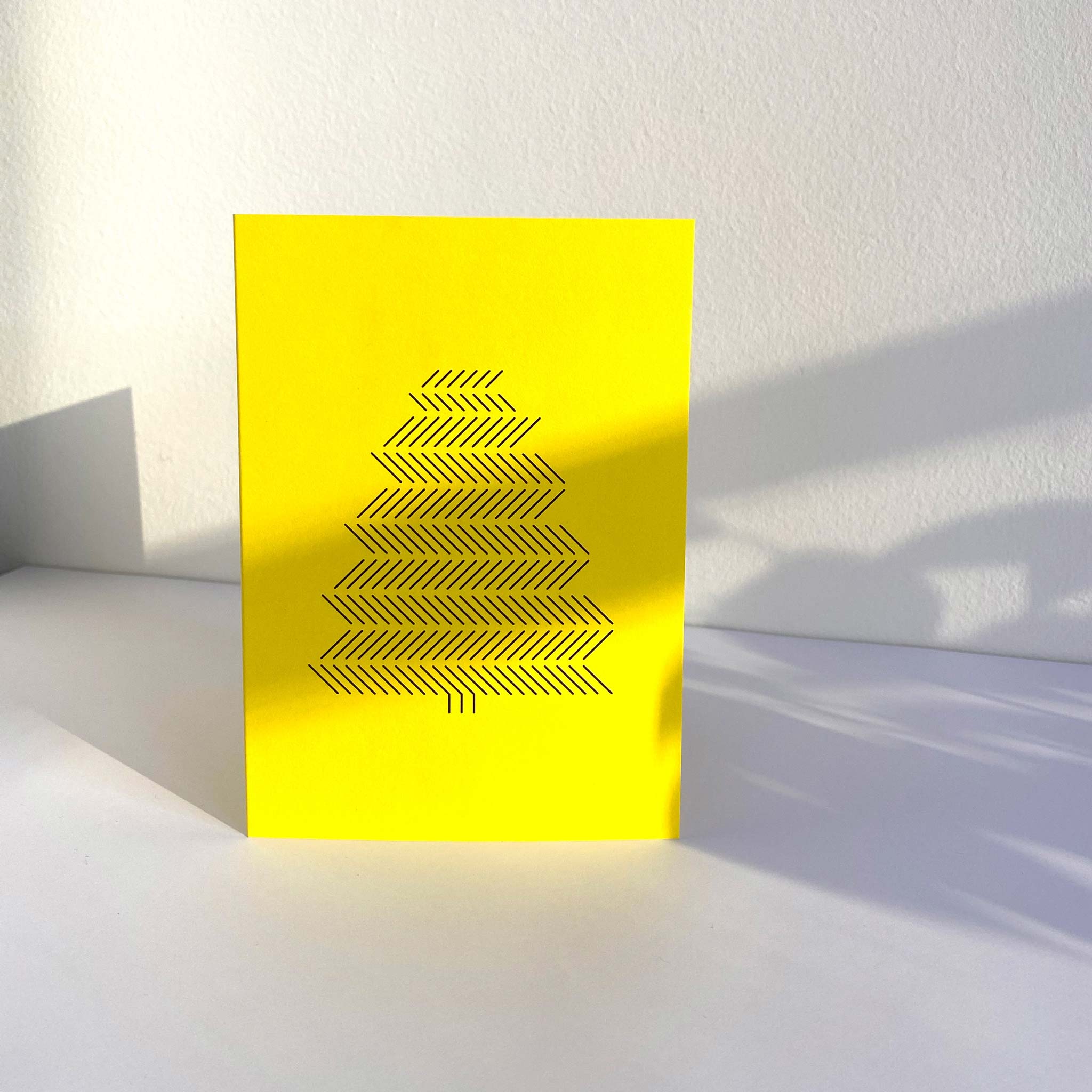 Standing yellow A6 christmas greeting card with black graphic print of pine tree