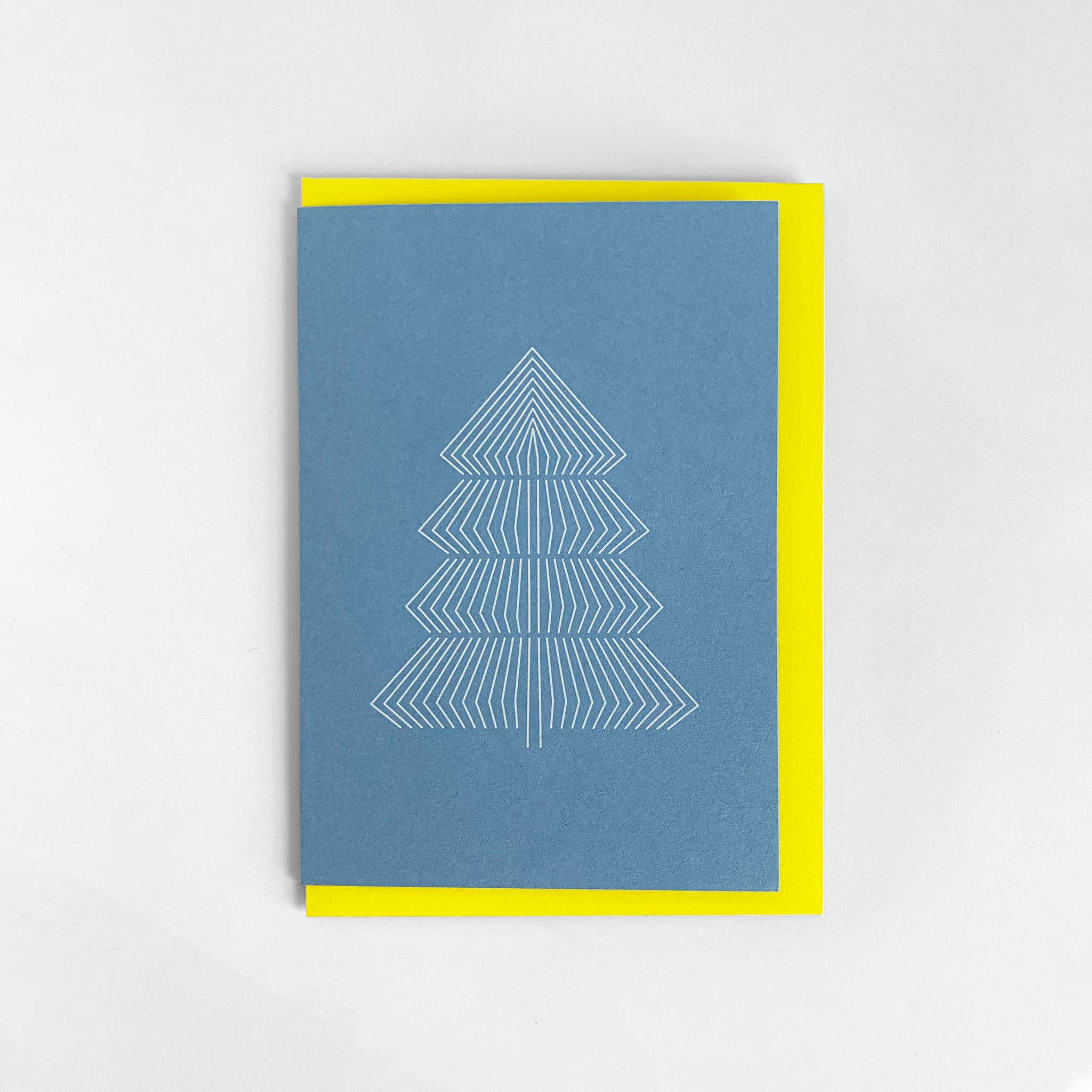 Sky blue A6 christmas greeting card with graphic print of fir tree and bright yellow envelope