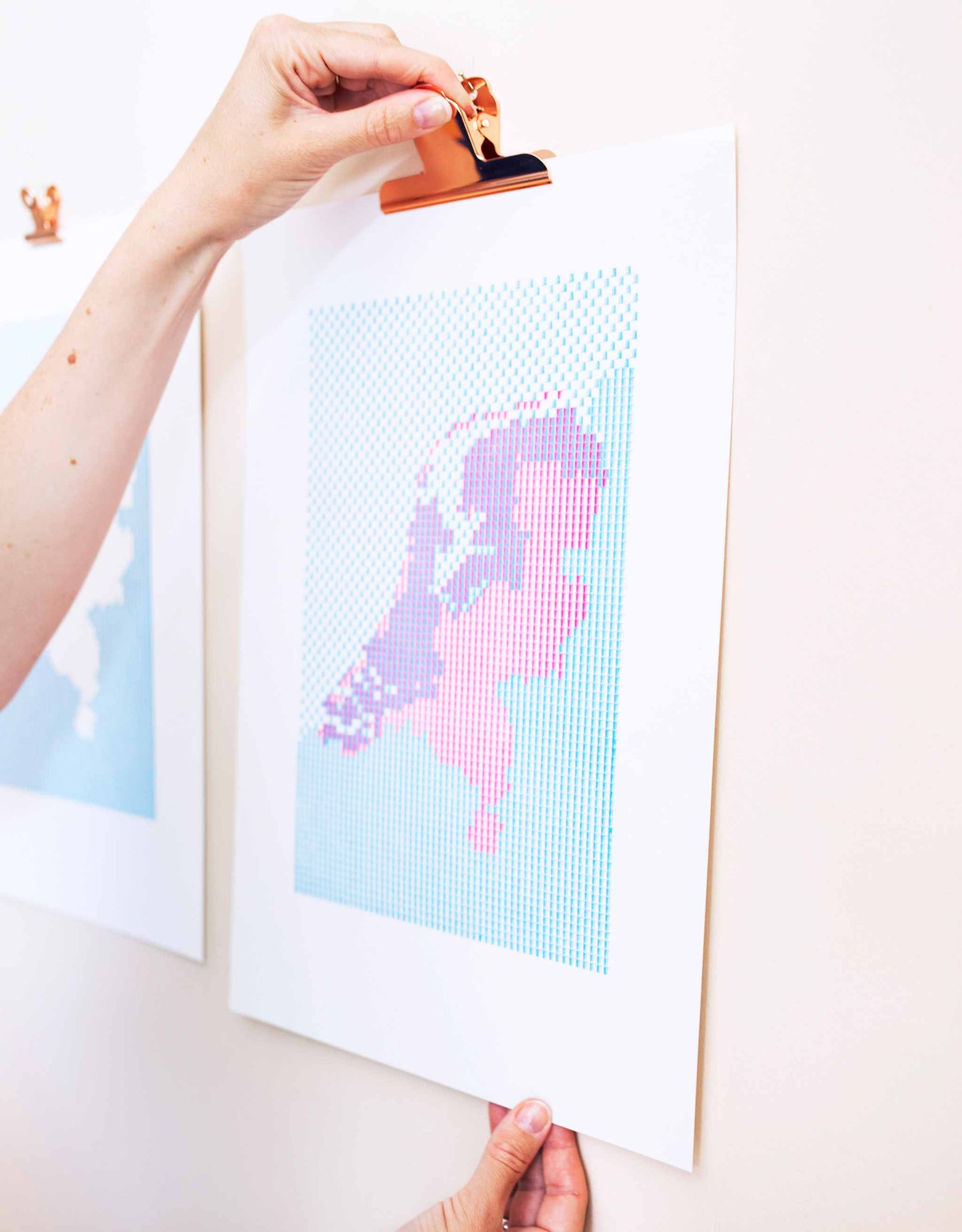 Hand clipping Letterpress patterned map of The Netherlands to wall. Magenta and blue patterned kaba ornaments.